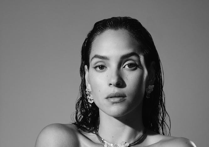black and white image of adria arjona wearing a white tube top and statement necklace