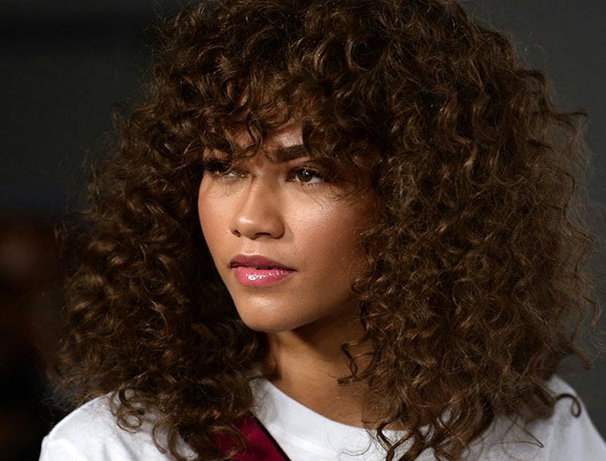 Close up photo of Zendaya with curly hair and bangs.