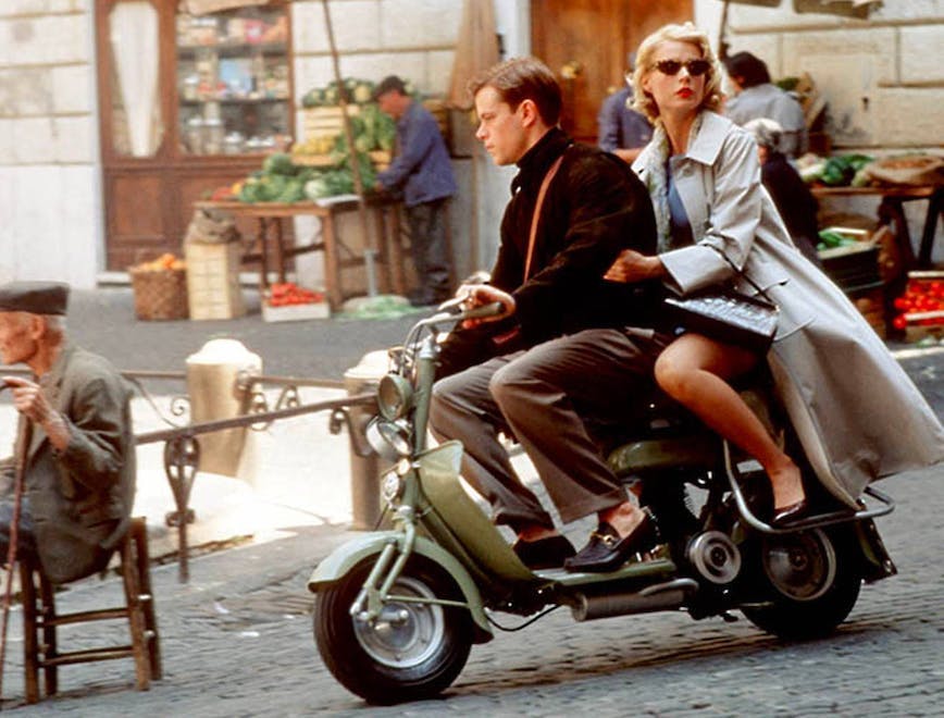 A woman and man riding a motor scooter on the streets of Italy.