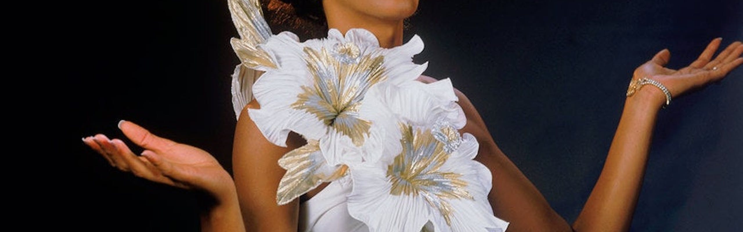 Houston posing while wearing a white dress with a large white flower