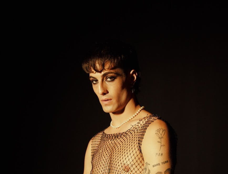 Man wearing a fishnet top and heavy undereye liner