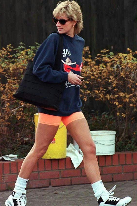 Princess Diana wearing a navy crewneck and neon orange biker shorts