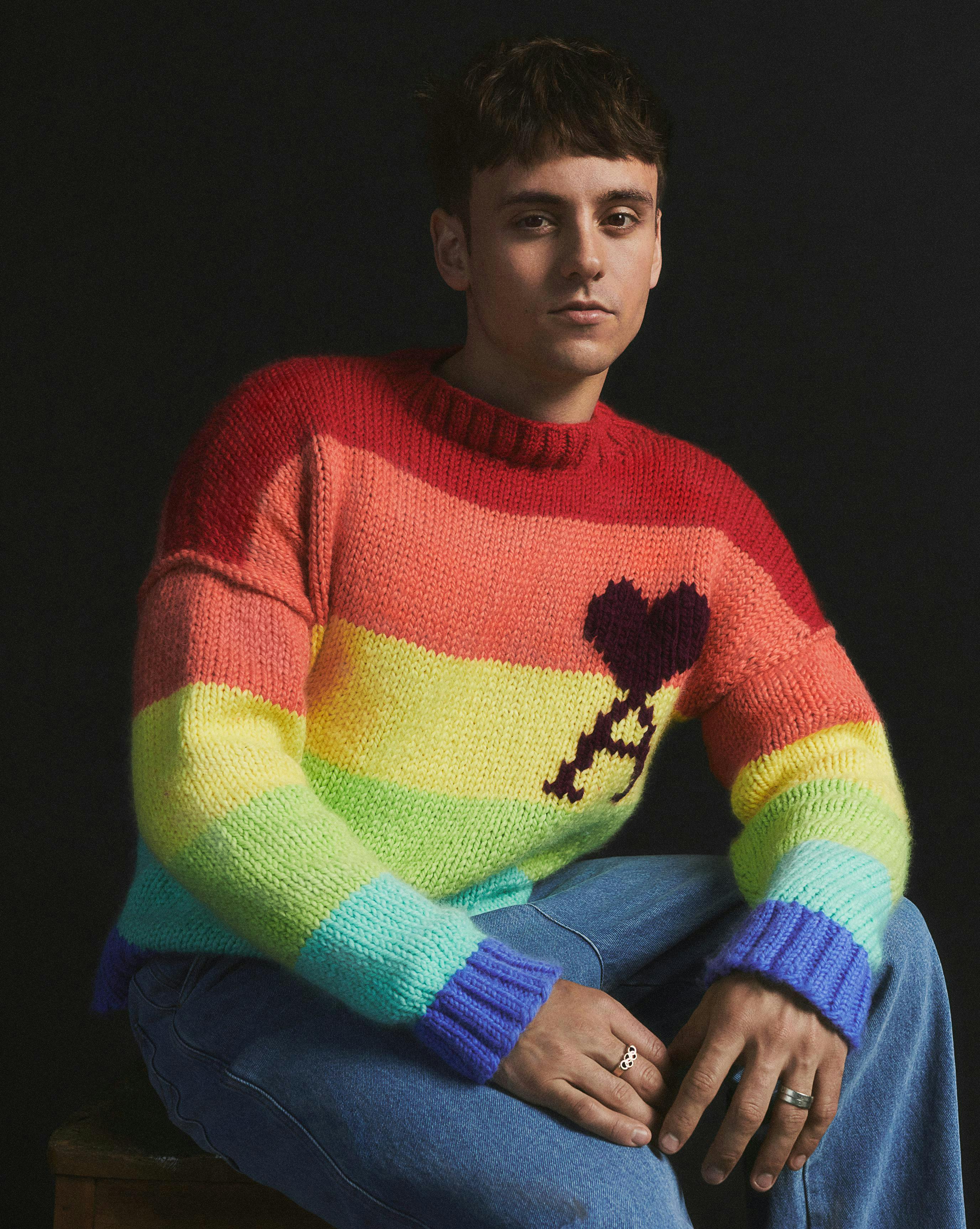 Athlete Tom Daley wearing a rainbow striped sweater.