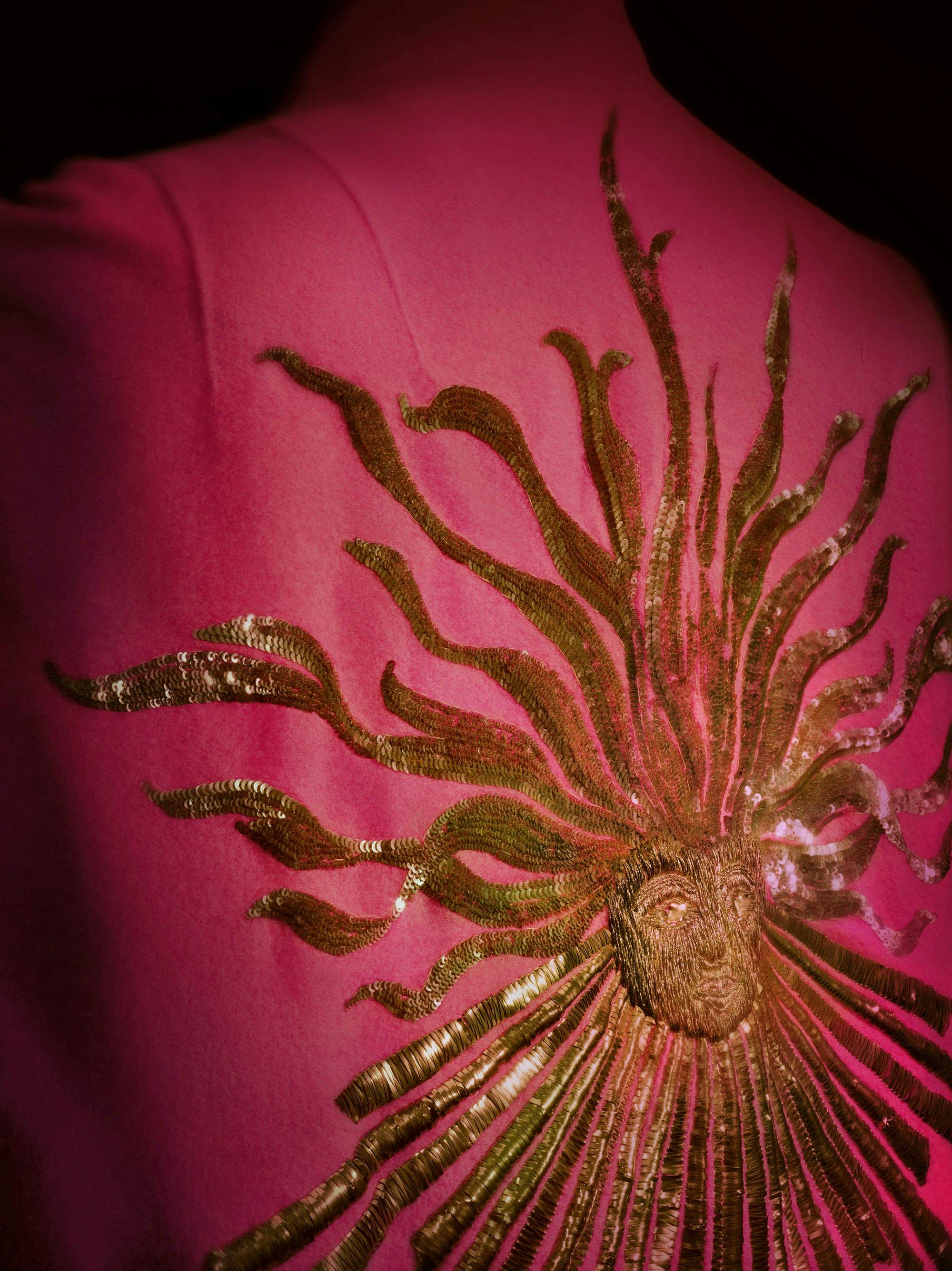 Close up of a pink coat with a gold sun emroidered on the back.