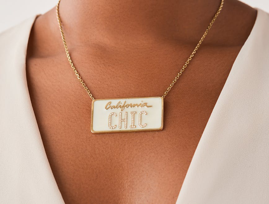A square white necklace, mimicking a license plate, with the word "California" in cursive and the word "chic" in capital letters. 