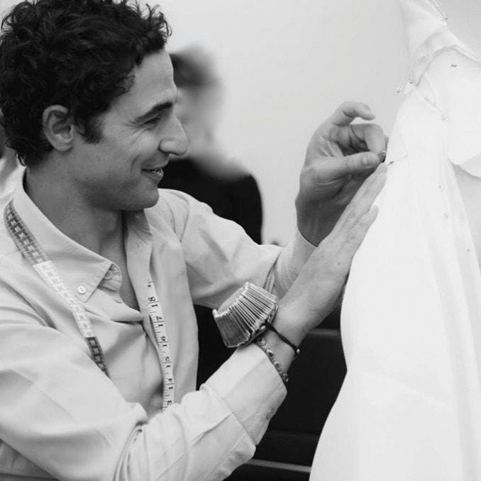 Black and white image of Zac Posen pinning fabric on a dress form