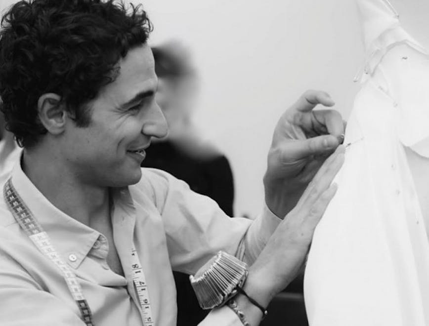 Black and white image of Zac Posen pinning fabric on a dress form