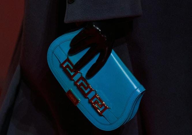 Model for Versace holding a sky blue clutch.