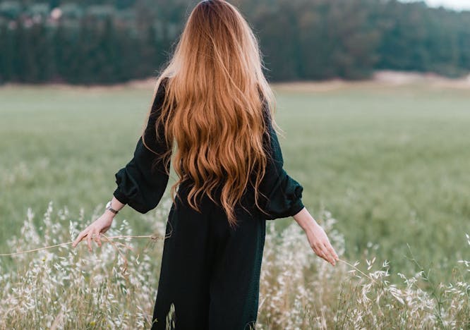 Woman with long hair standing in a field.