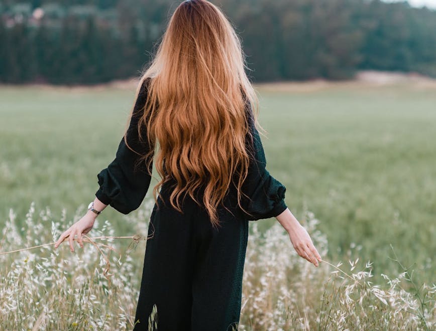 Woman with long hair standing in a field.