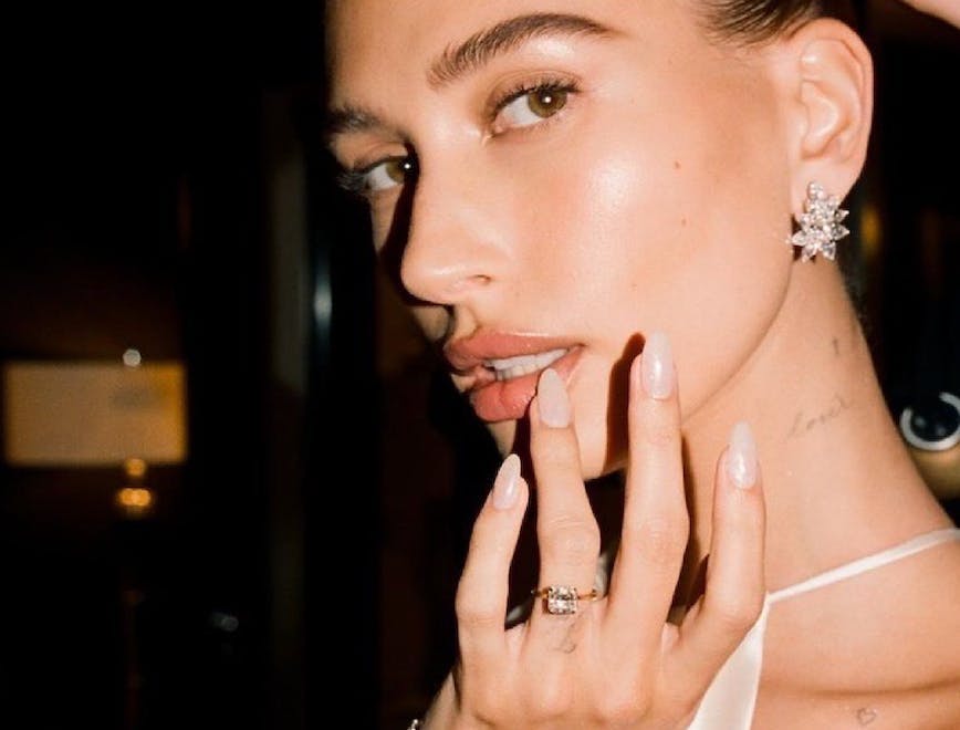    Hailey bieber showing her manicure to the camera wearing sparkly earrings