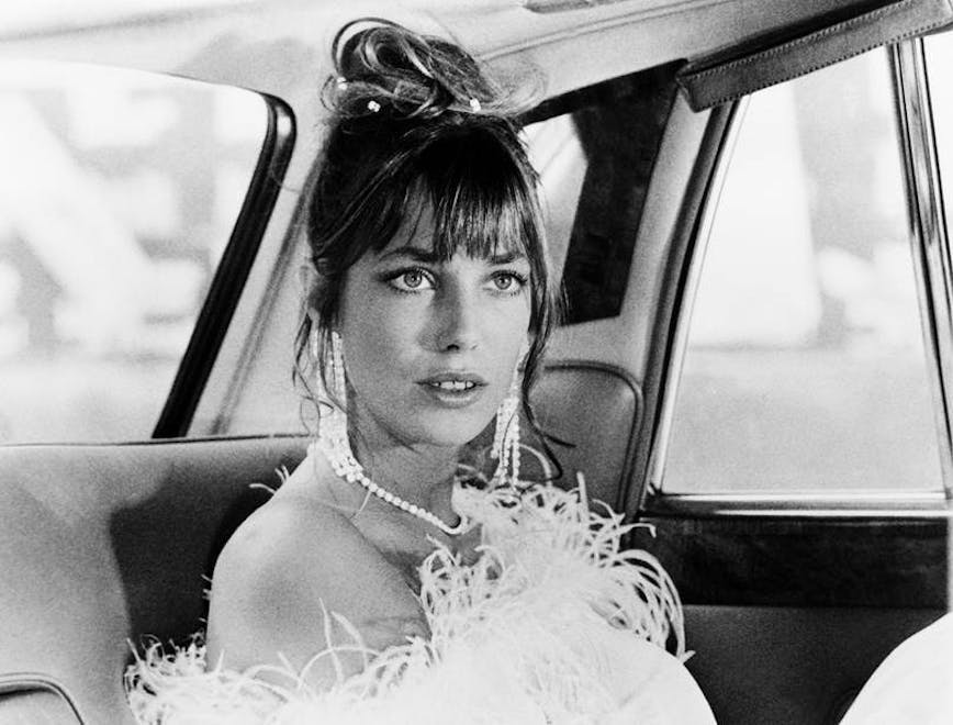 jane birkin in the back of a car in feathers and pearls with her hair up