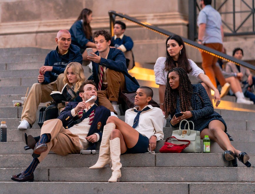 The cast of the Gossip Girl reboot sits on The Met steps.