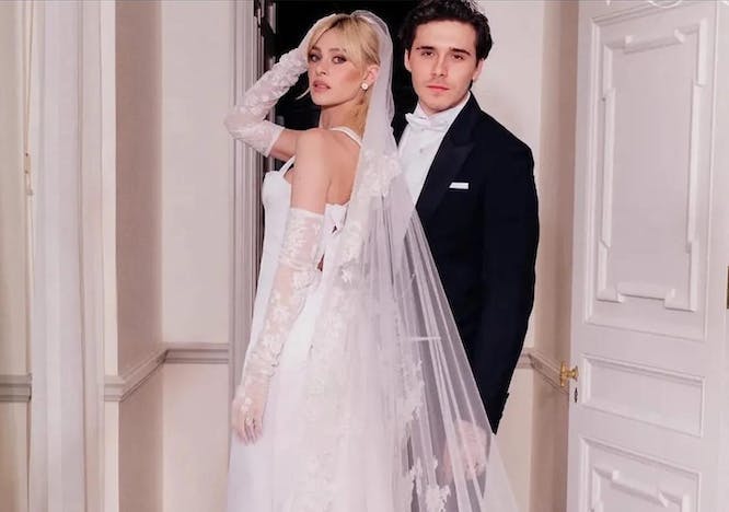 Nicola Peltz in her white gown and cascading veil and Brooklyn Beckham in his black tuxedo posing after their wedding ceremony.