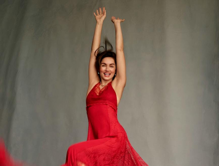 Ana de Armas jumping in a red lace gown.