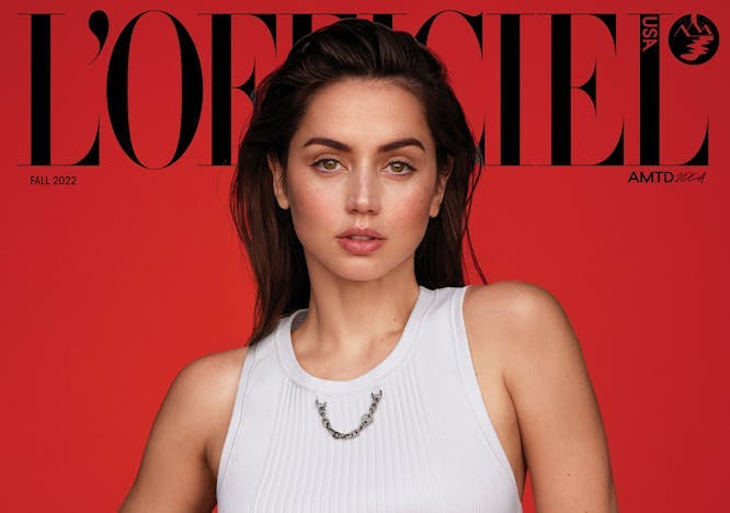 L'OFFICIEL USA Fall 2022 cover of Ana de Armas in front of a red backdrop wearing a white tanktop with a chain detail and brown corduroy pants with a leather waistband.
