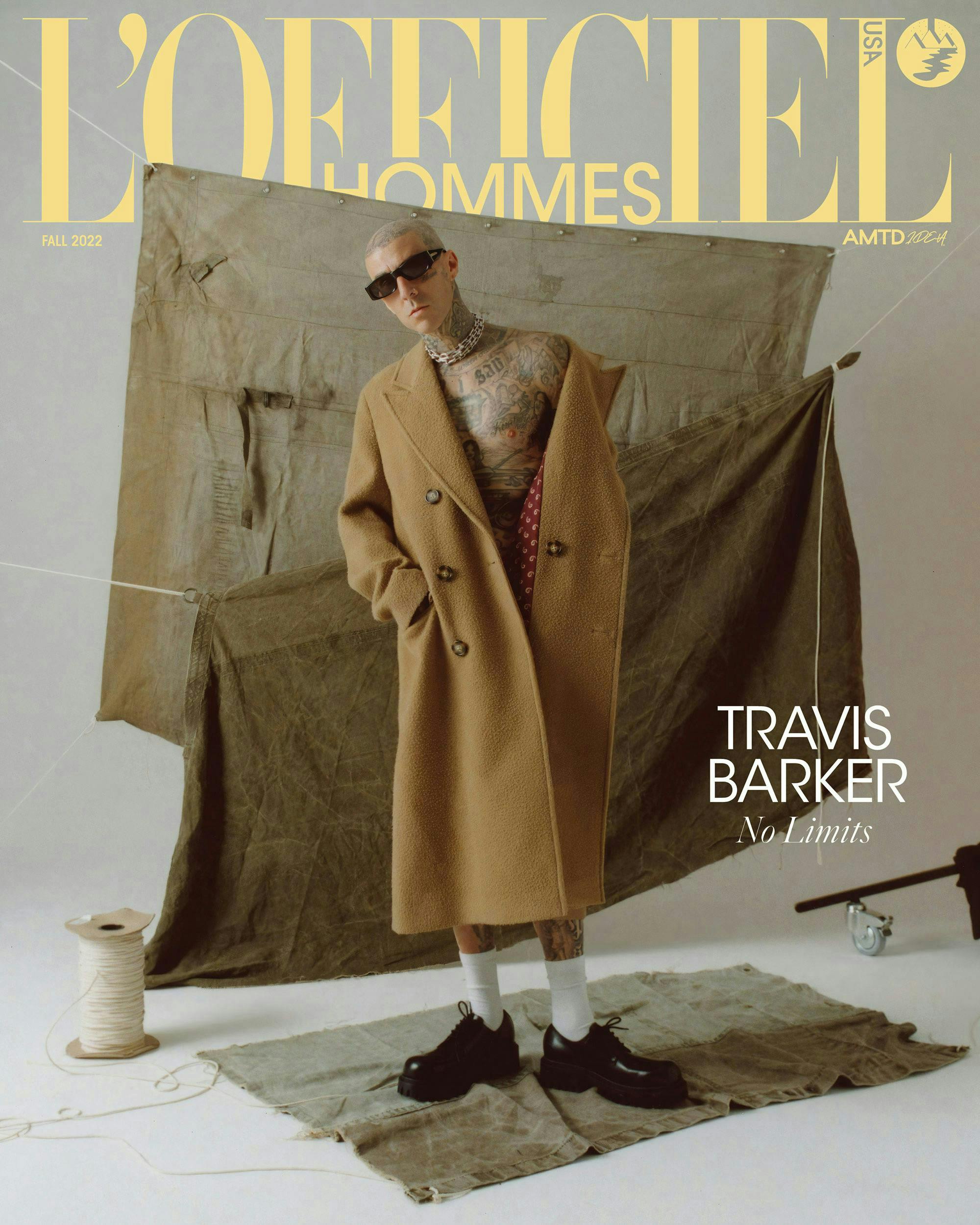 Travis barker tan coat brown blankets gray background