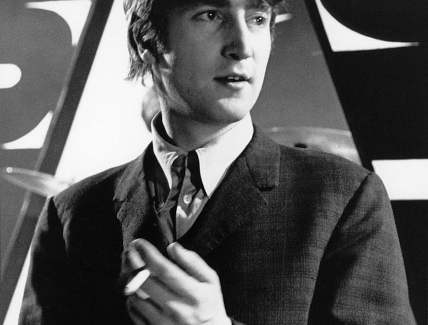 John Lennon in a suit while looking away from the camera.