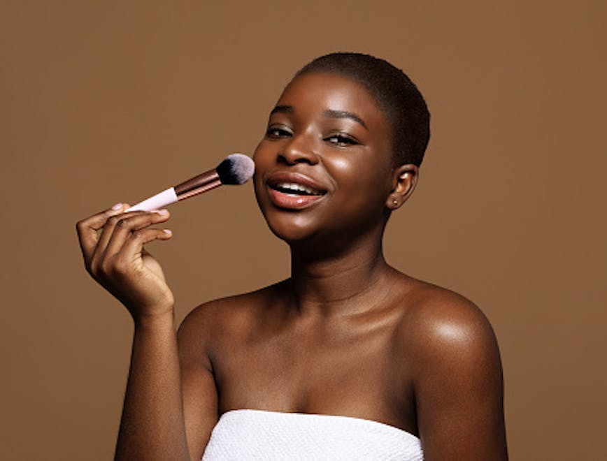 woman holding makeup brush brown background