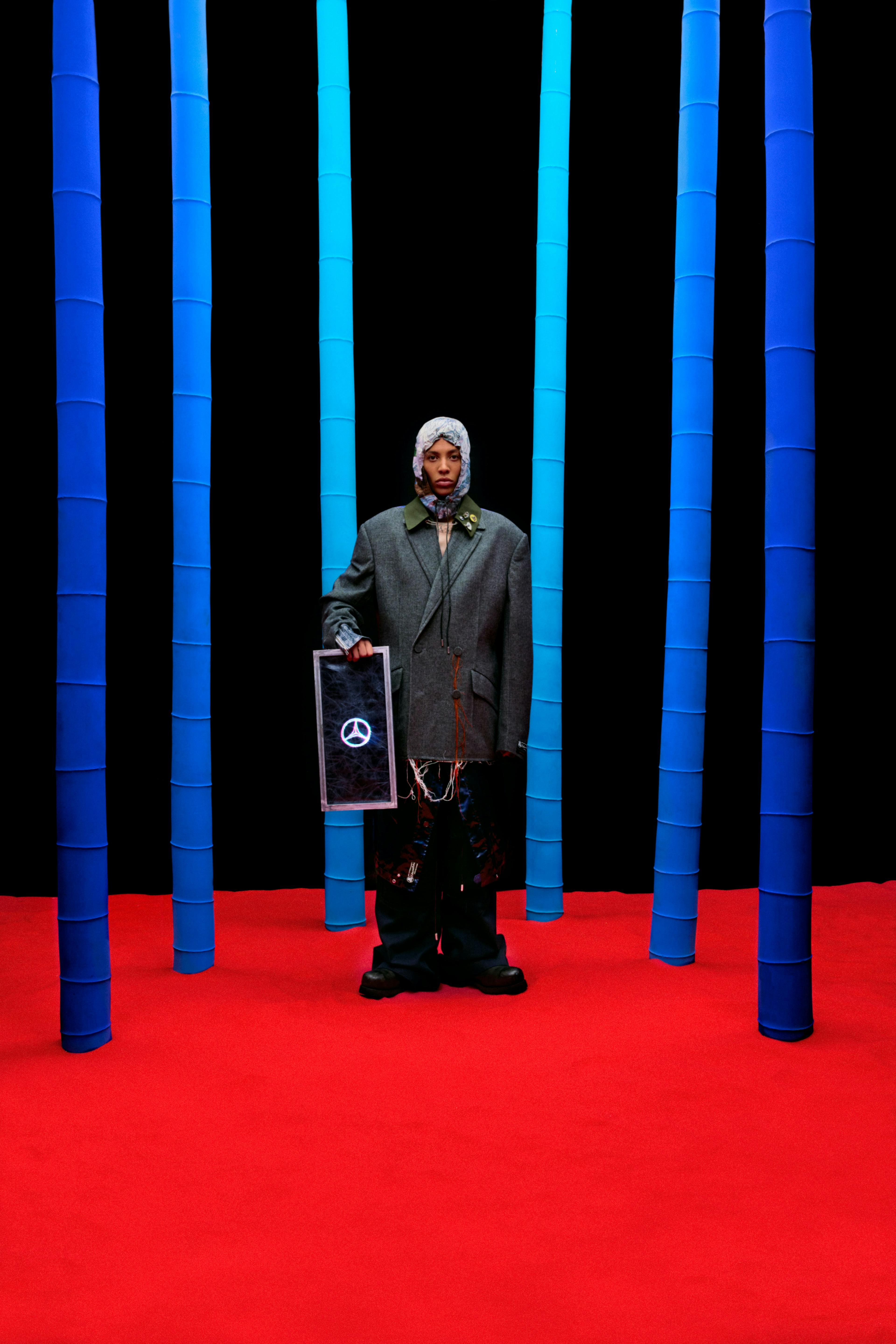 Kai Isaiah Jamal in Valentin Lessner red floor black backdrop blue poles