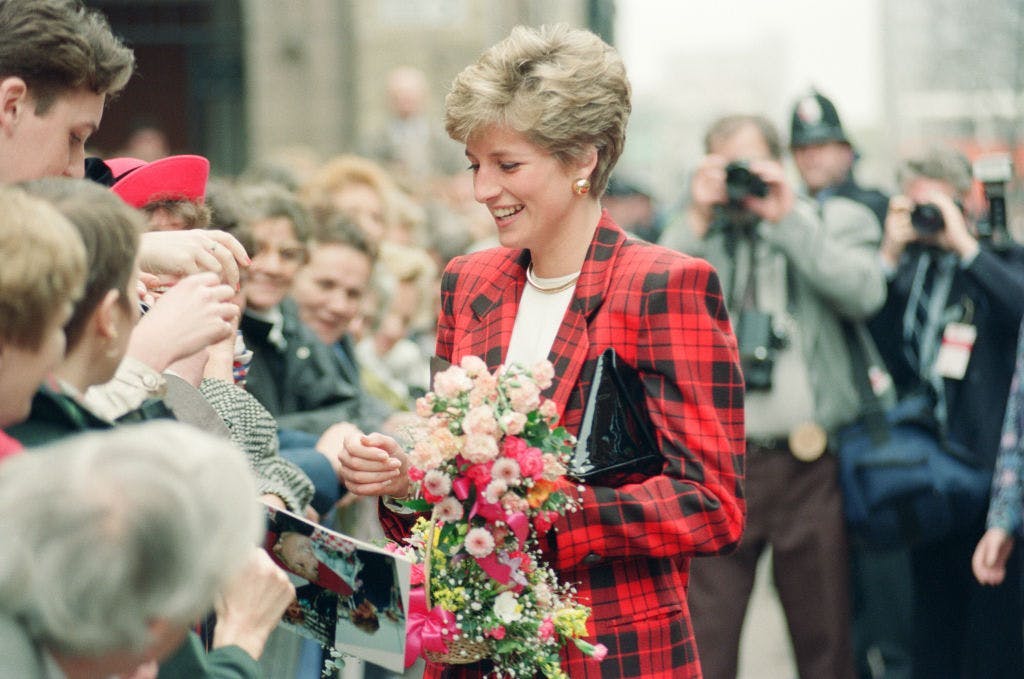 princess diana wearing plaid holding flowers in a crowd of people