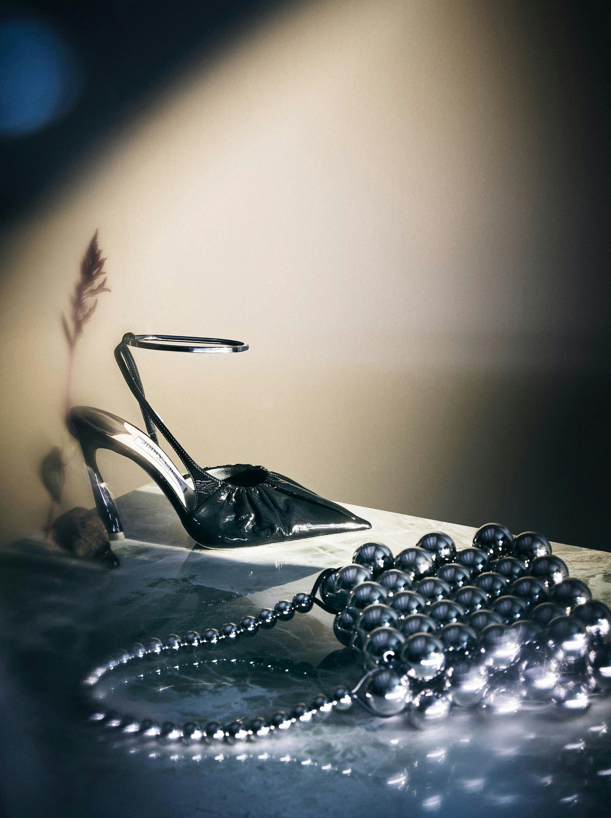 black shoe and silver purse on table tan wall