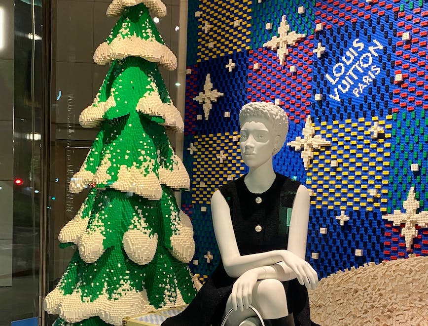 A window display showing a mannequin sitting down and a Christmas tree.
