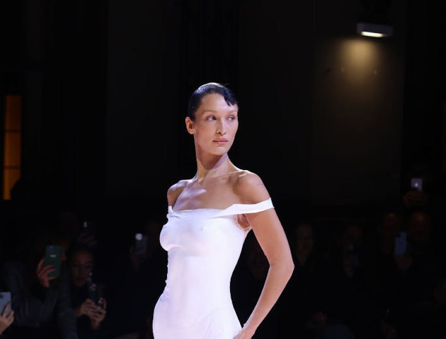 A model in a white dress while posing on the runway.