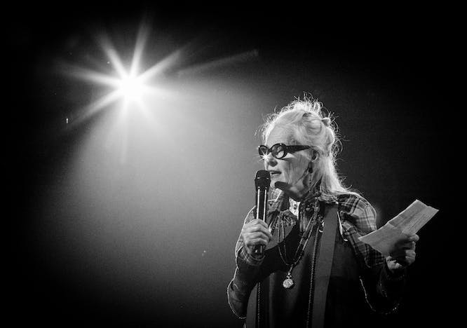 Black and white photo Vivienne Westwood with a microphone under a spotlight
