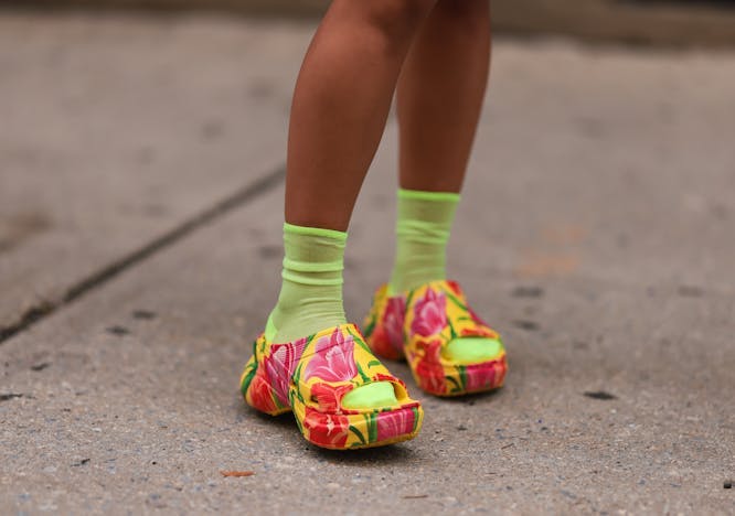 legs in colorful clogs neon green socks cement street