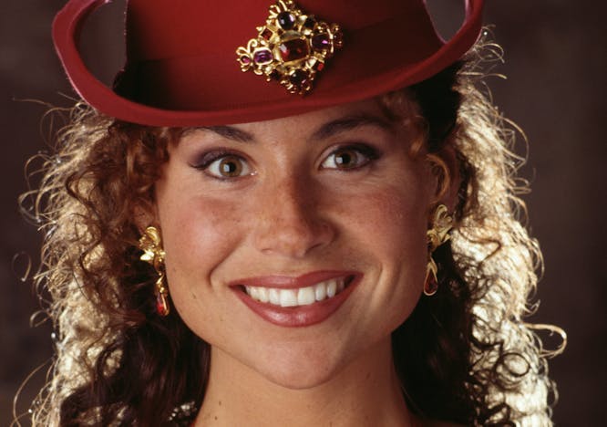 Minnie Driver wears red cowboy hat and bra with flowers on it.