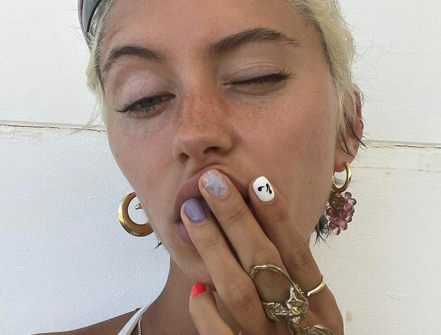 Woman taking a selfie with fun nail designs.