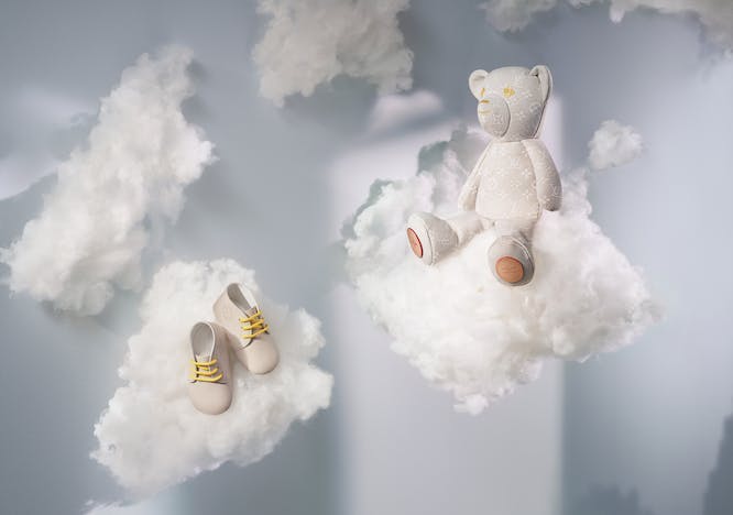Stuffed bear and shoes sitting on clouds.