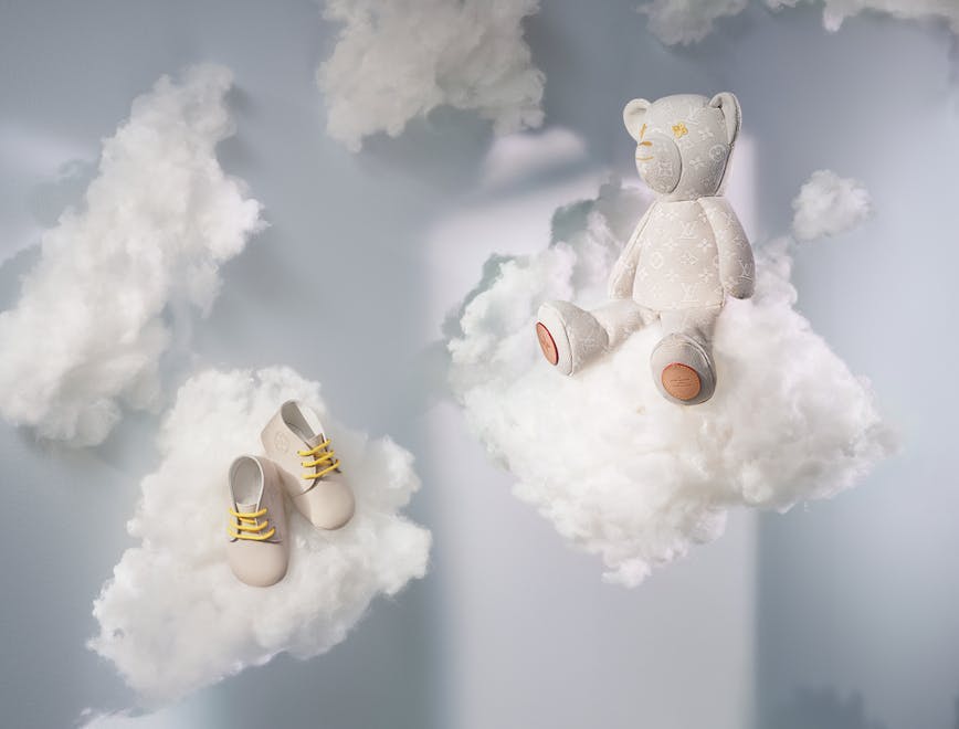 Stuffed bear and shoes sitting on clouds.