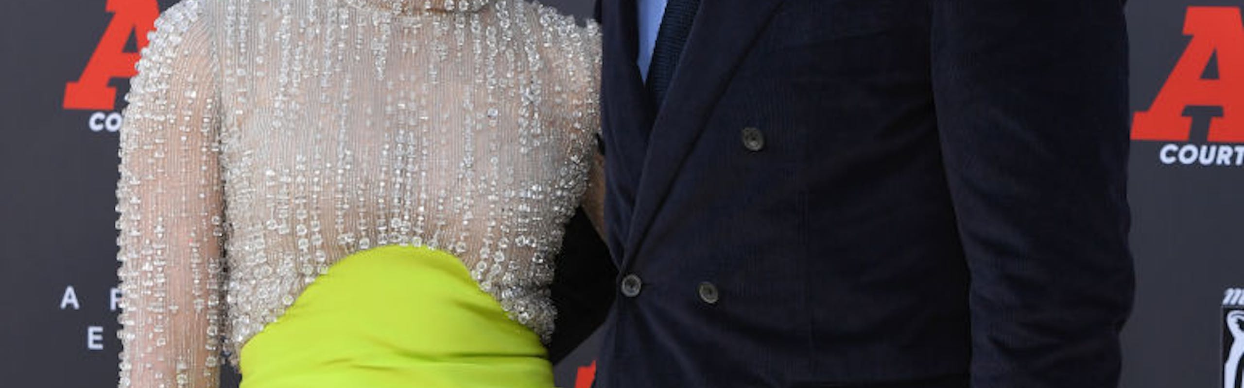 Jennifer Lopez in a neon dress and Ben Affleck in a black suit.