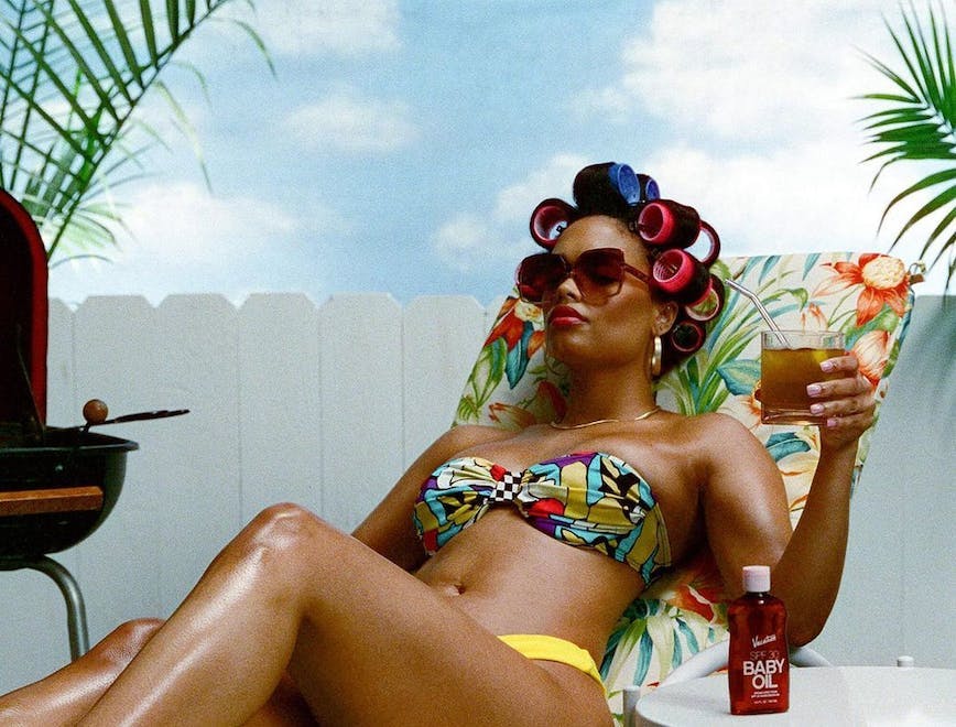 A model with hair rollers and wearing a bikini while lounging.