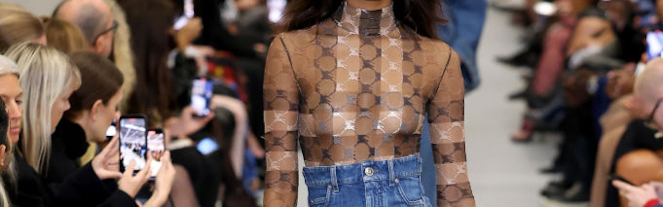 A model in a mesh top and denim skirt.