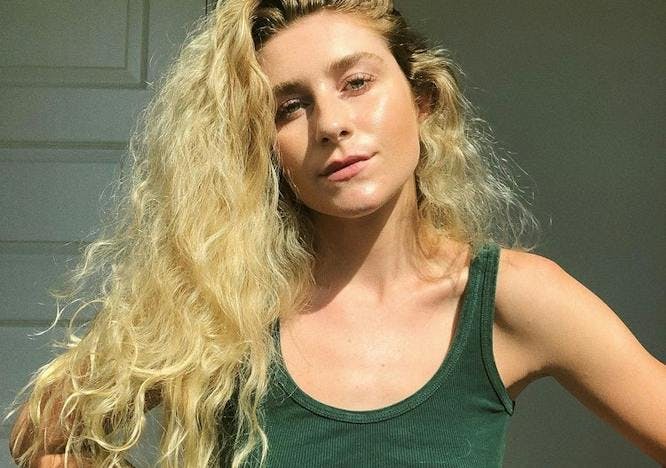 Courtney Taylor Olsen wearing a green tank top and her hair swept to the side.