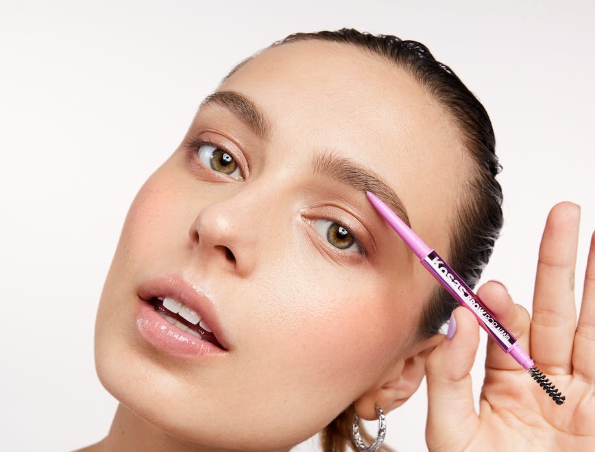 A model holding a brow pencil; new august beauty launches 2023
