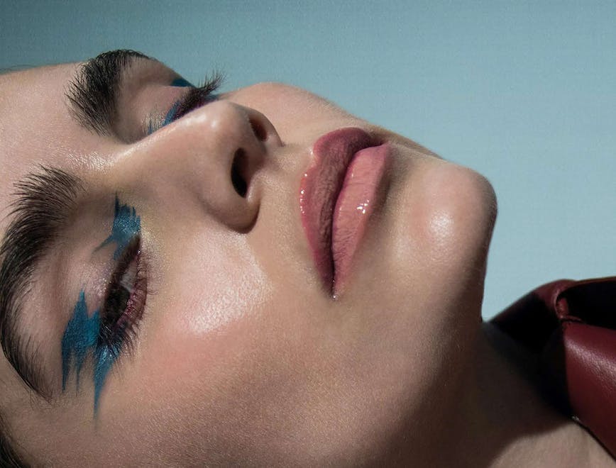 A model in blue eyeliner and nude lipgloss.