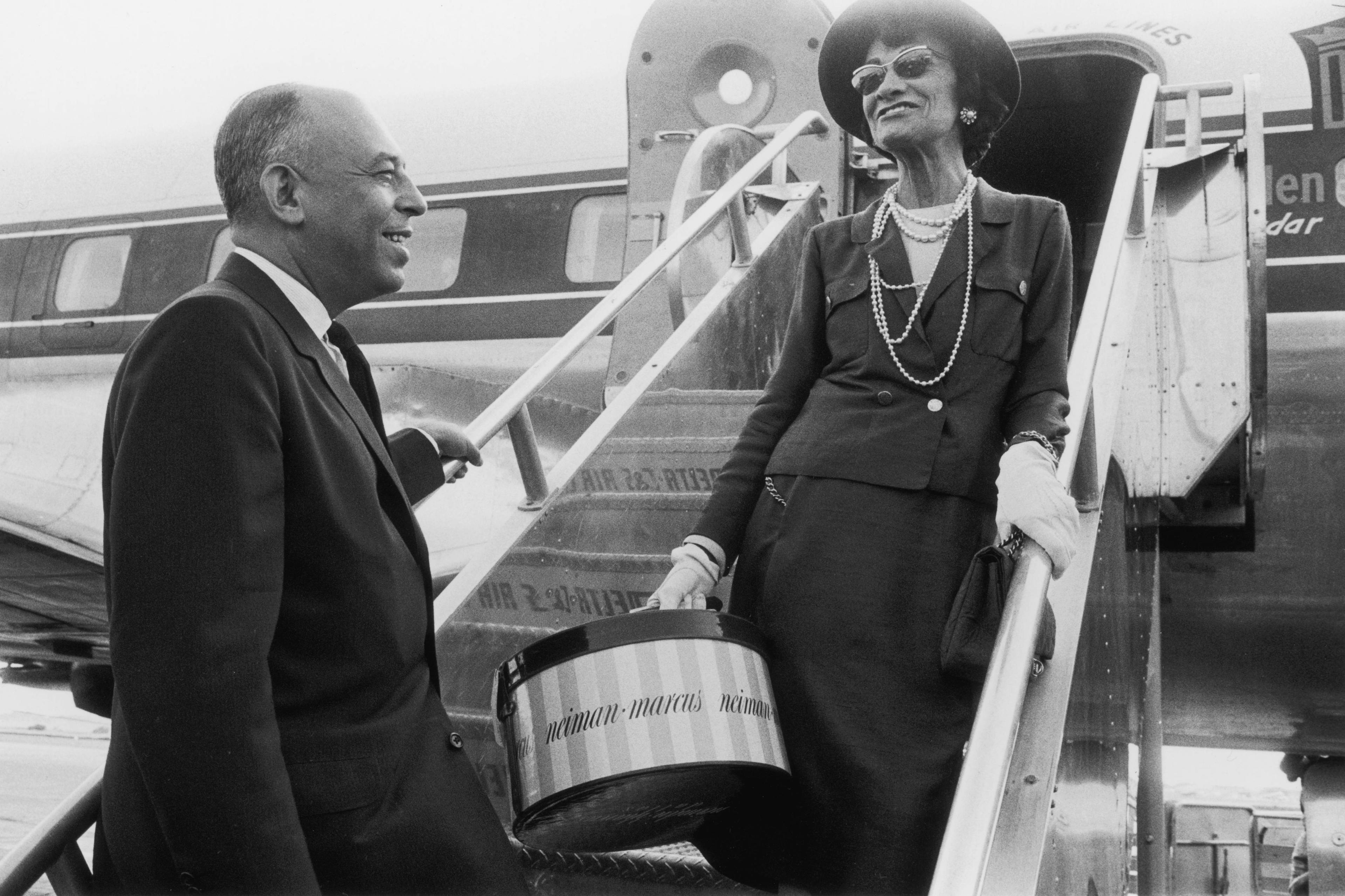 Chanel family brand history; Coco Chanel boarding a plane after the opening of a new Neiman-Marcus store.