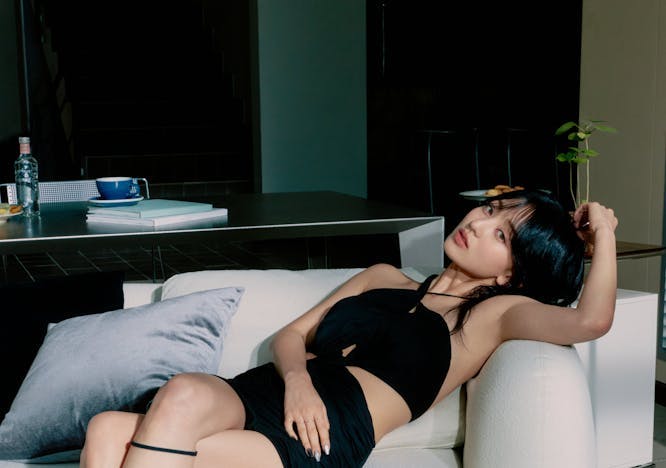 Jihyo sitting in a white hair wearing a black mini dress