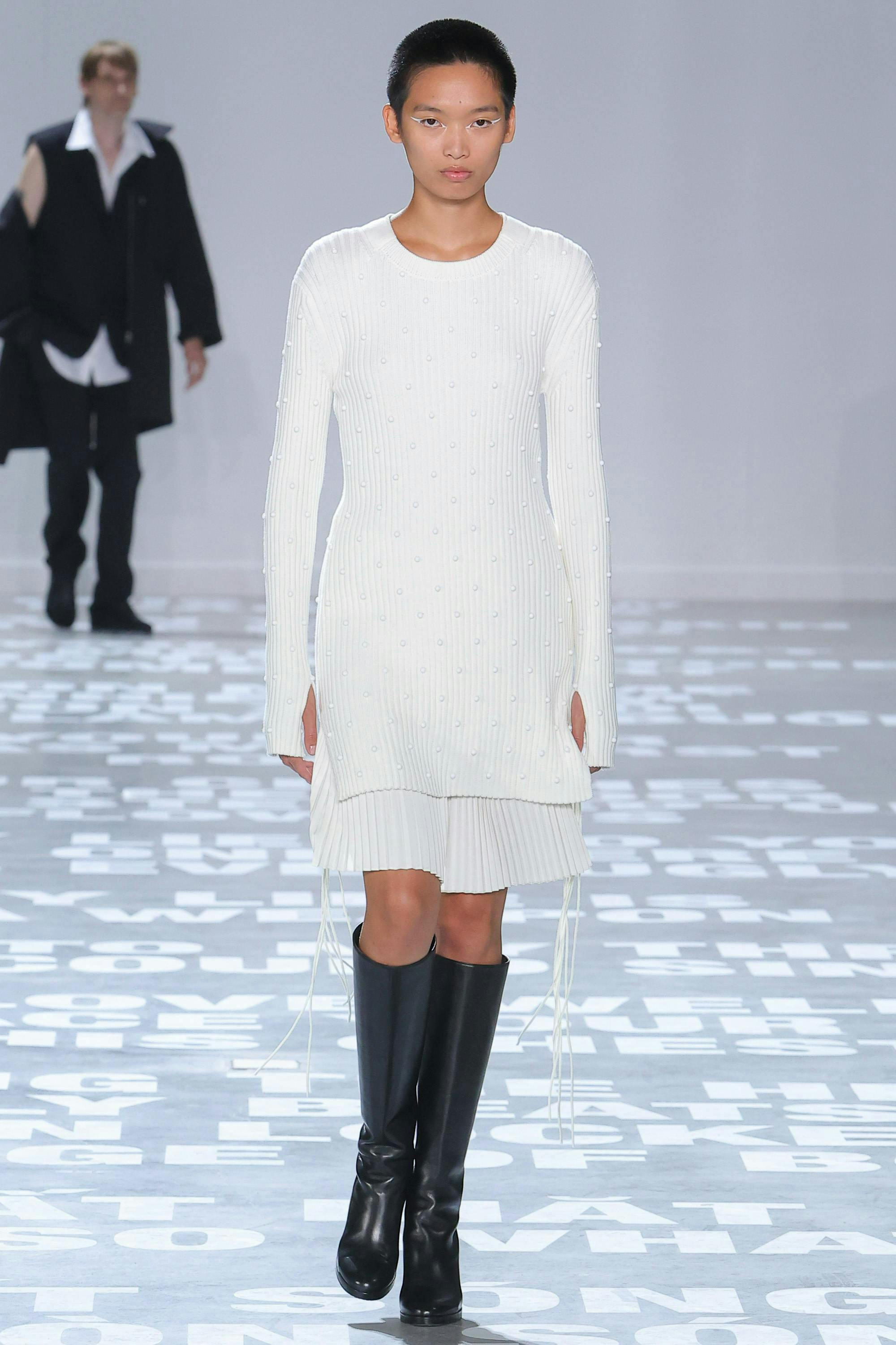 model in white top and skirt with black boots
