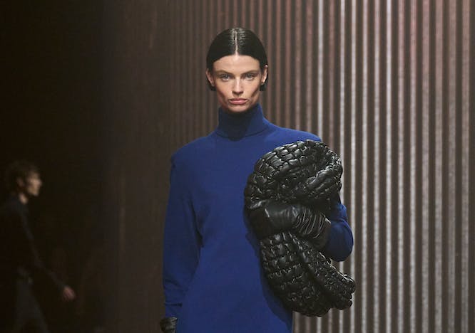 model in blue knit maxi dress holding black woven bag