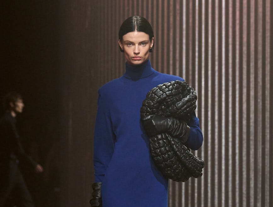model in blue knit maxi dress holding black woven bag
