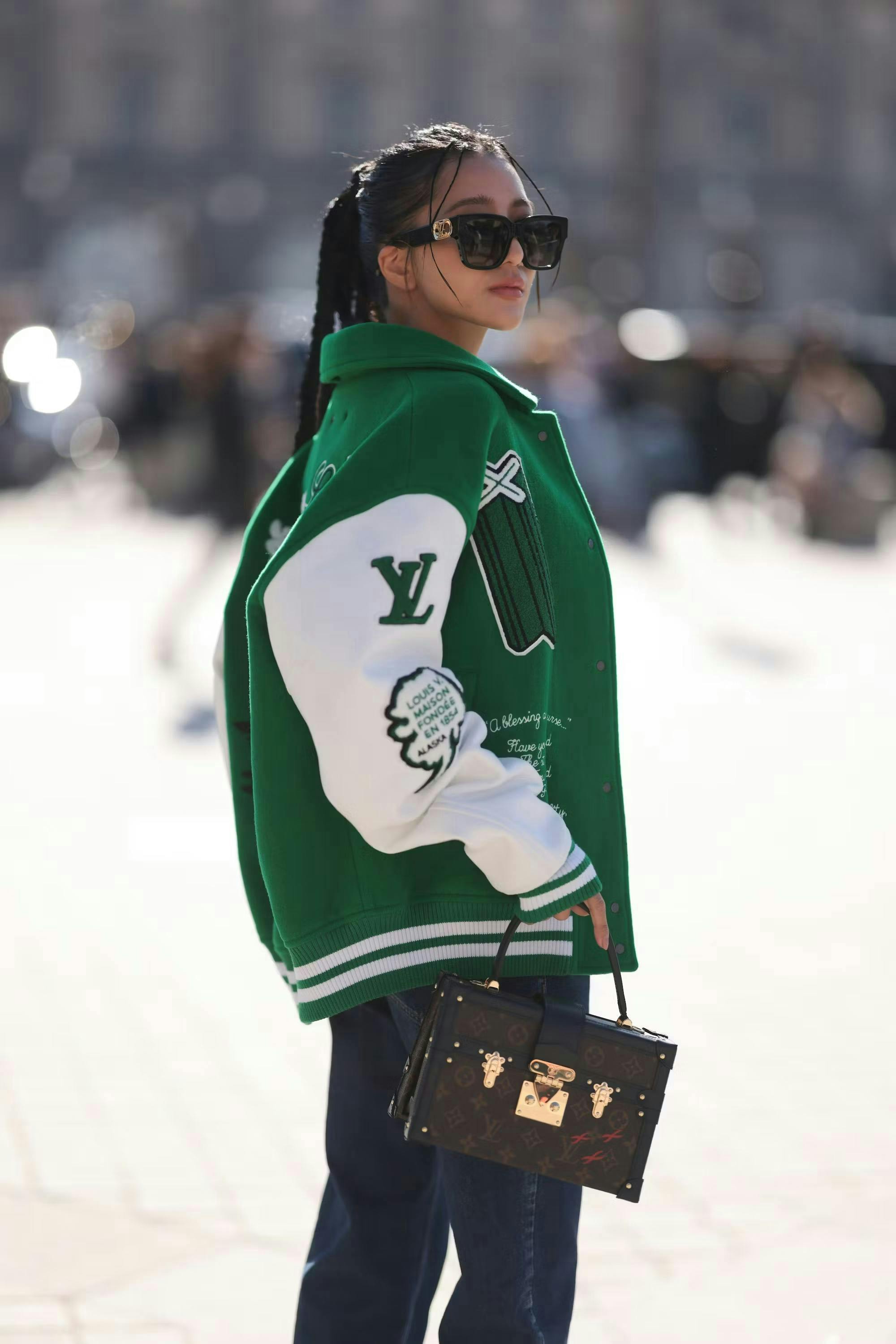 woman in green varsity jacket holding louis vuitton mini bag