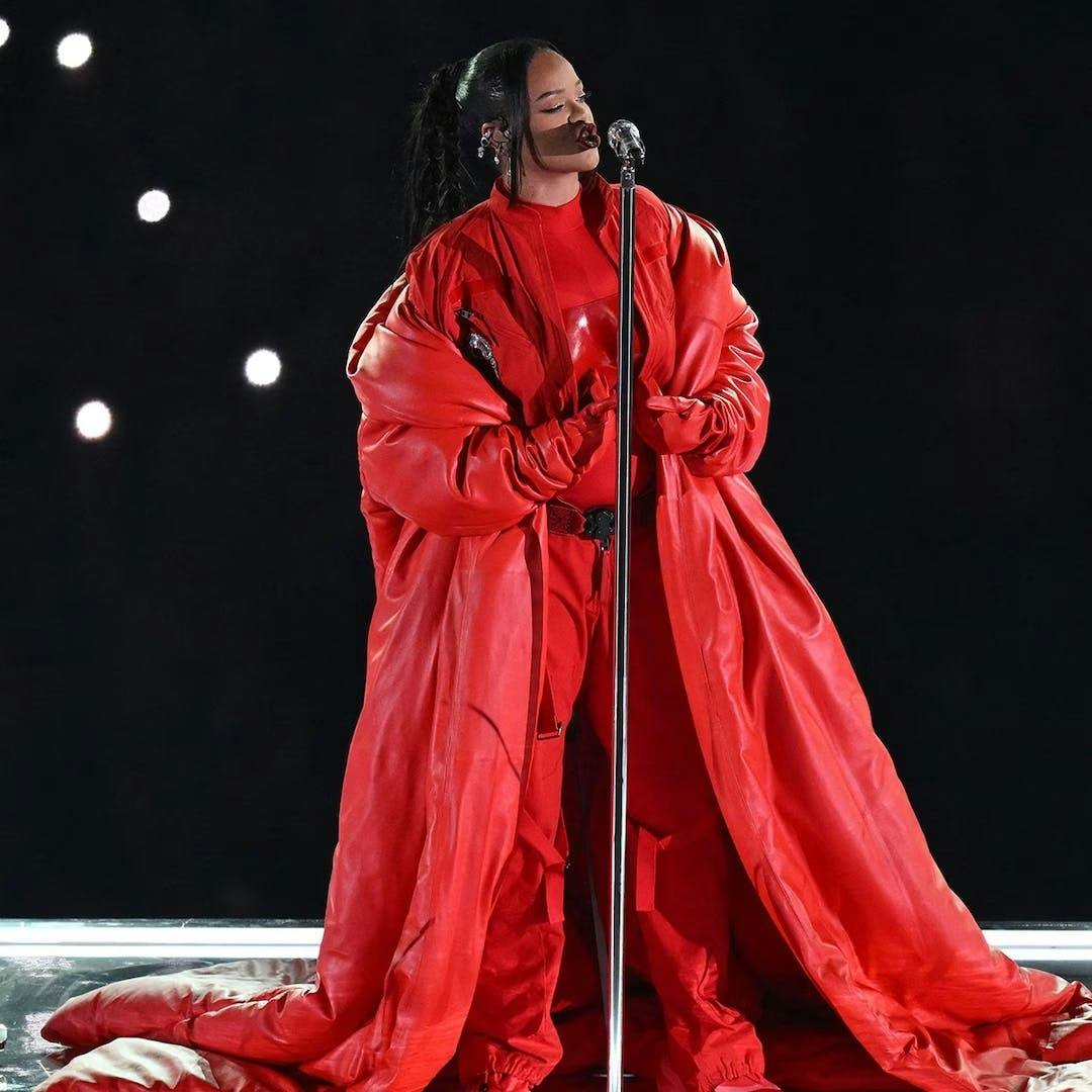 rihanna in a red jumpsuit, overcoat, and bustier