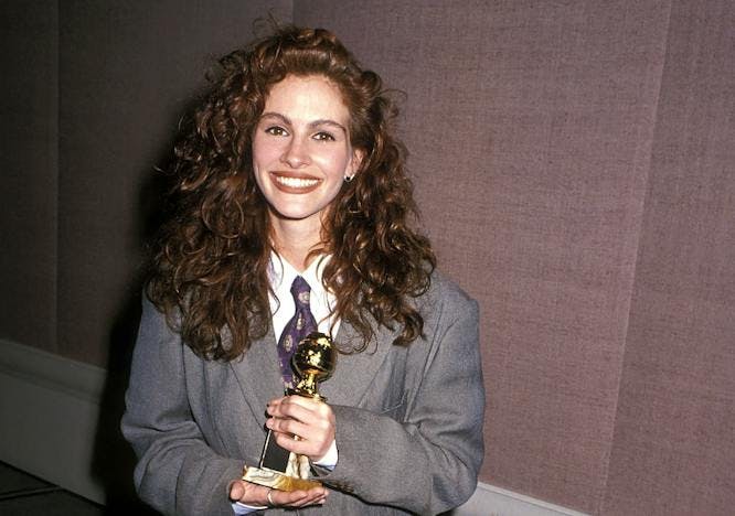 young julia roberts in a grey suit holding a gold statuette