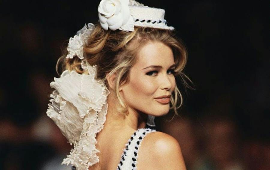 young claudia schiffer modeling as a 90s supermdoel wearing a white headpiece.