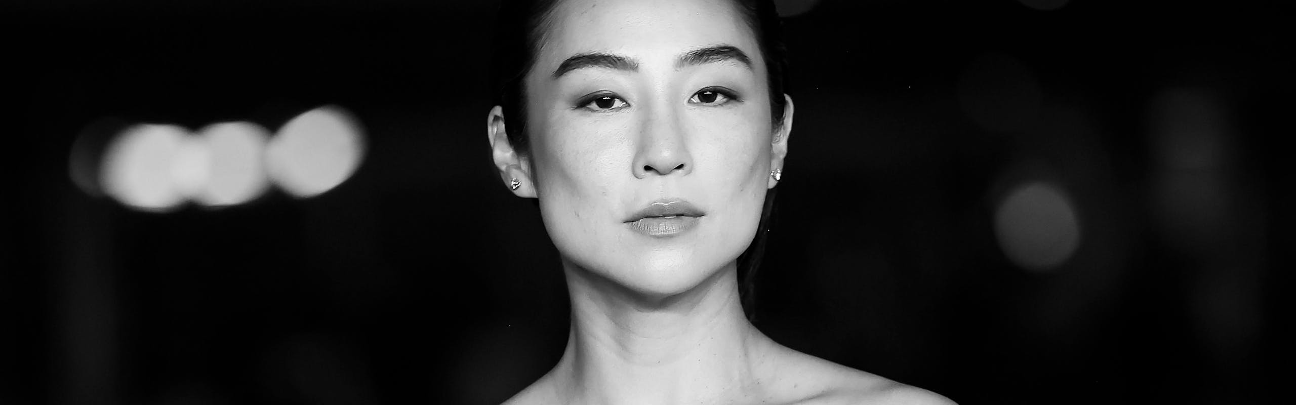Black and white image of Greta Lee in a dress with puffy sleeves